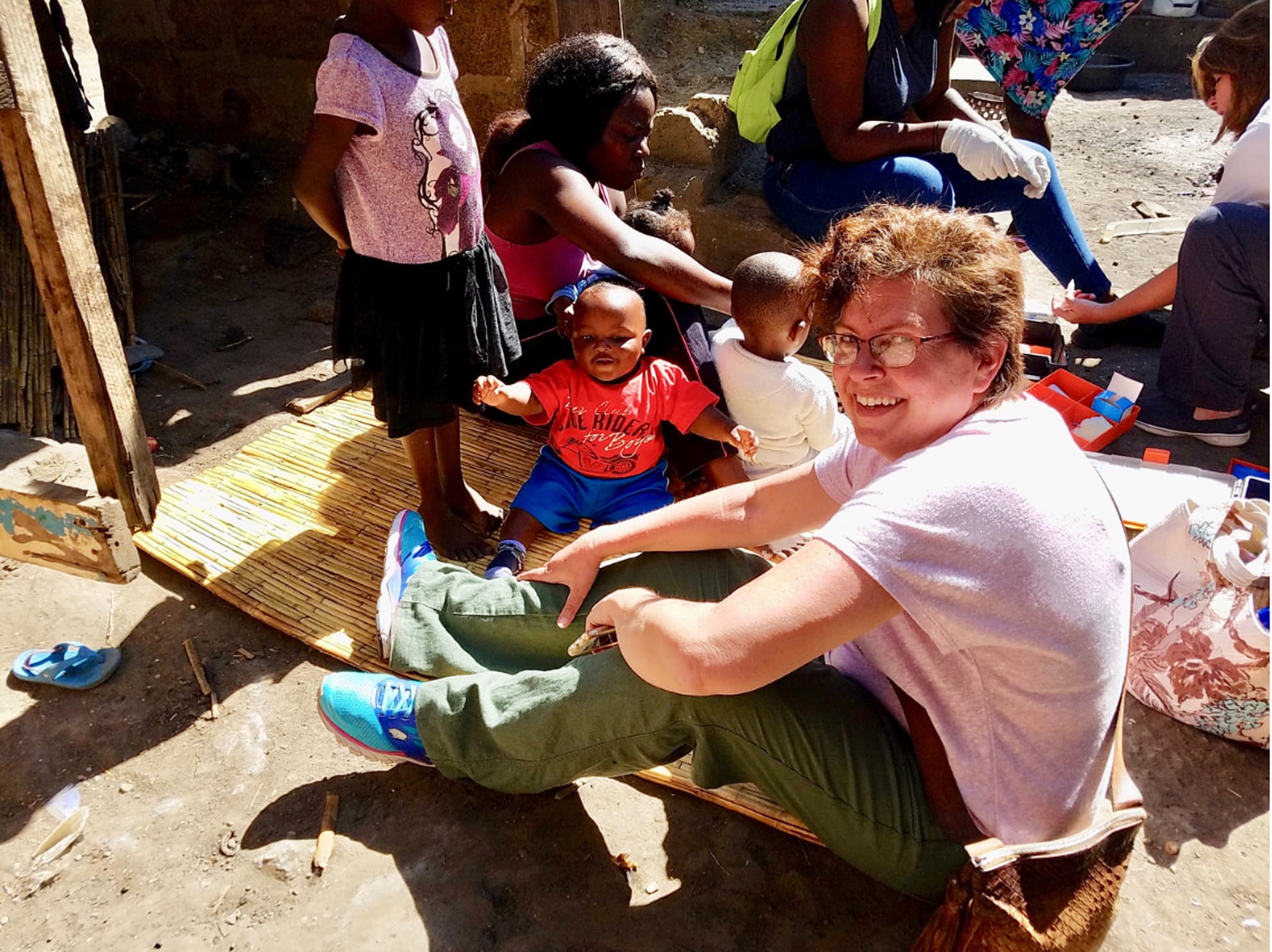 Michelle Meade sitting on the ground with children in Africa
